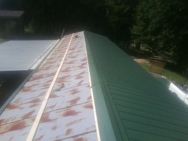 Old rusted panels beside newly installed green metal roofing — Wind Damage Roof Repair by Roofing Brothers in Hazelwood