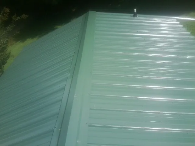 New green metal panels meeting at the ridge of a roof — Flat Roof Repair work by our crew in Hazelwood
