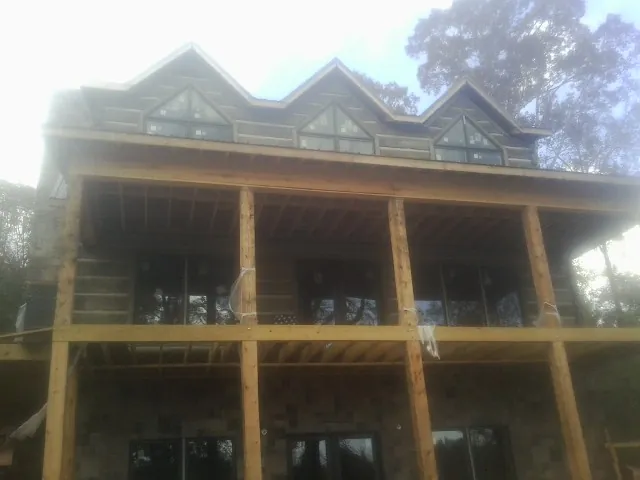 Dormers and porch framing on a large log home under construction — Roof Coating work by our crew in Hazelwood