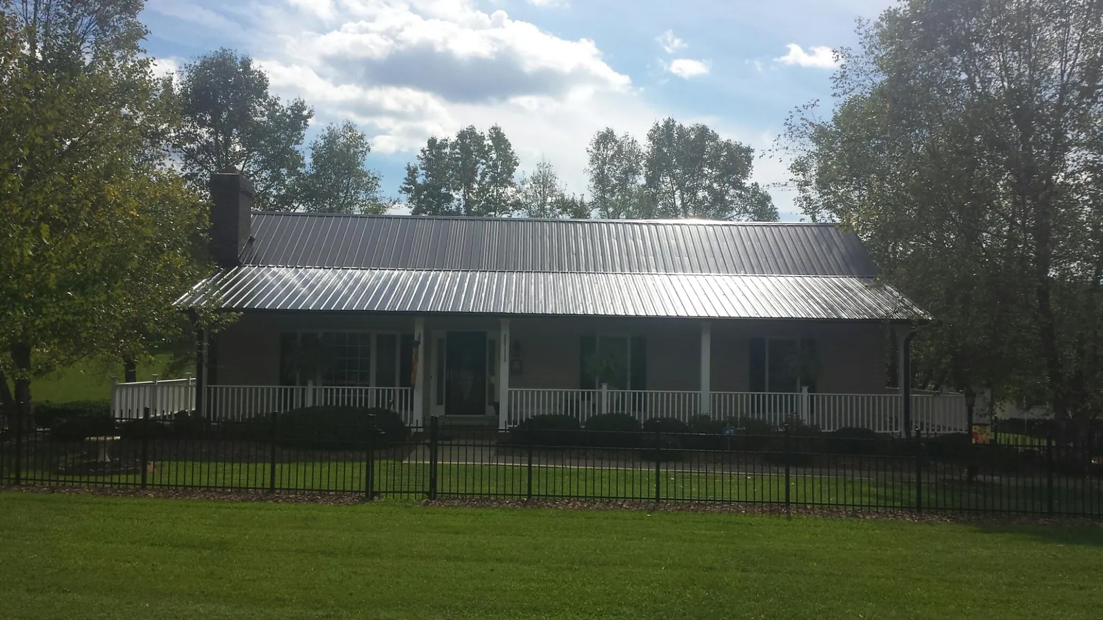 Gray metal roof on a brick ranch with a full width front porch — Gutter Guard Installation work by our crew in Hazelwood