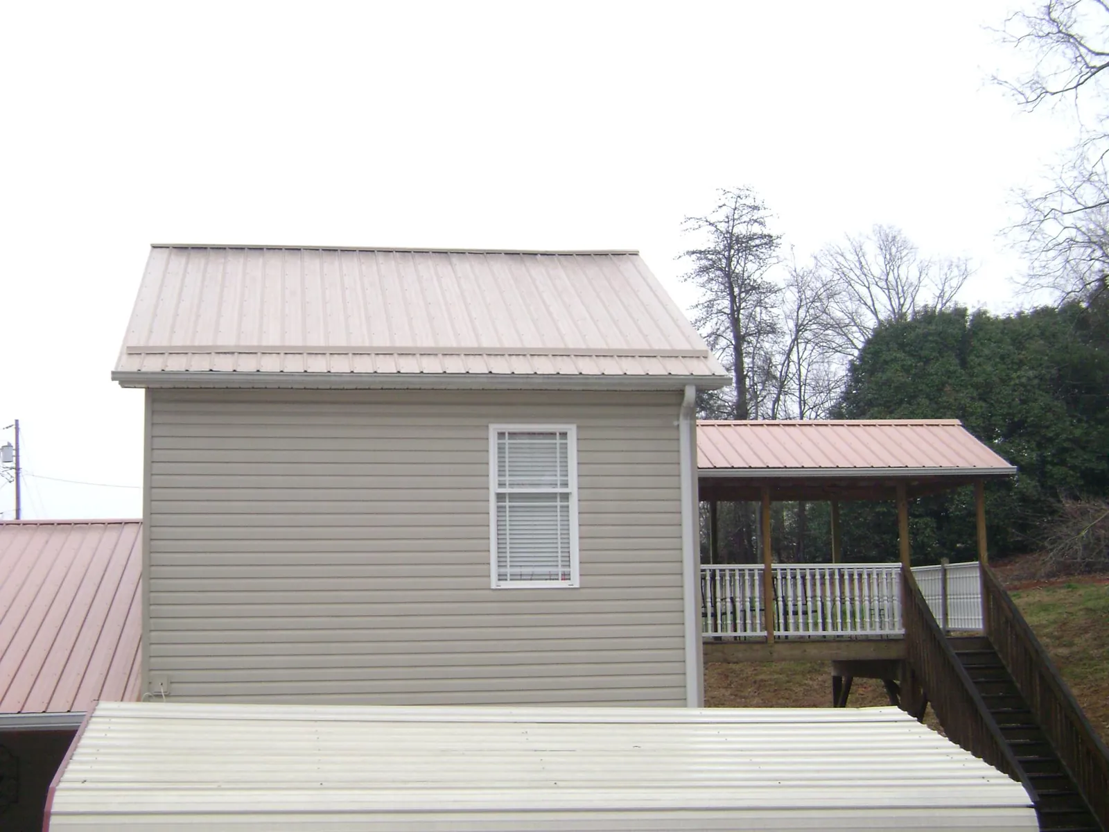 Tan metal roofs on a two story addition and attached porch, from a Roof Replacement job in Hazelwood