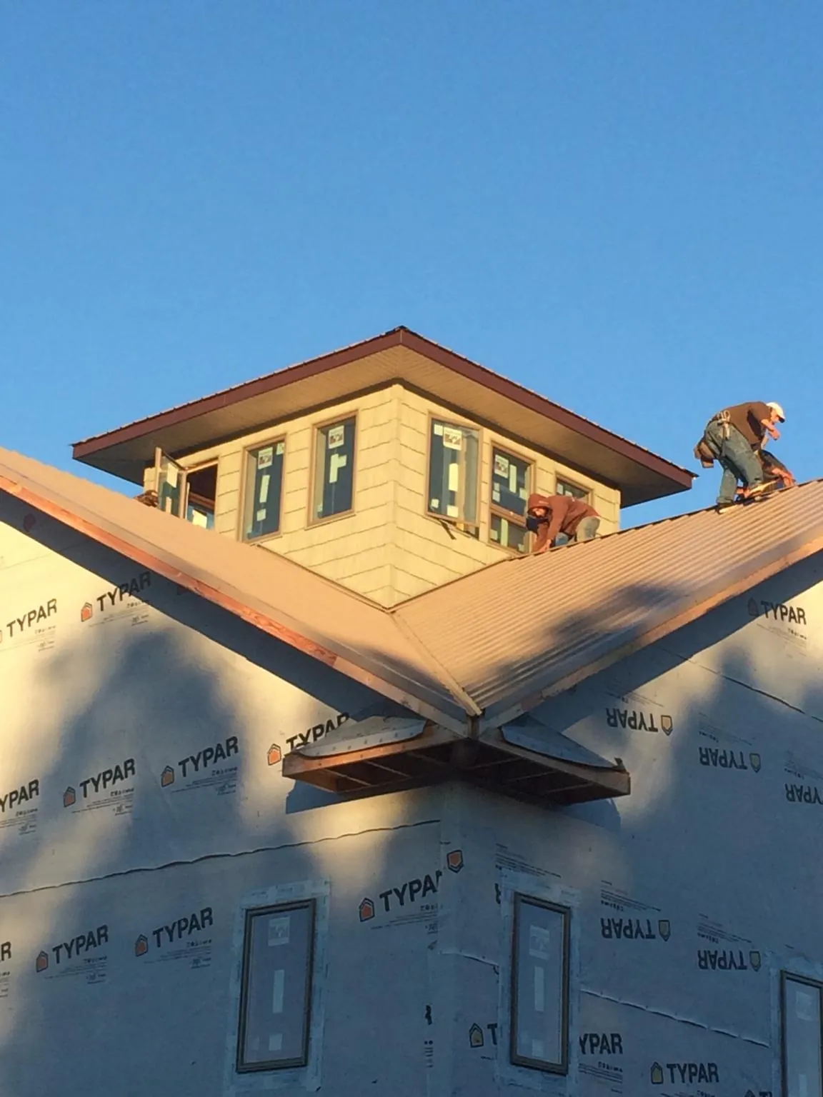 Roofers working around a rooftop cupola on a new metal roof at sunset — Roof Waterproofing in Hazelwood by Roofing Brothers